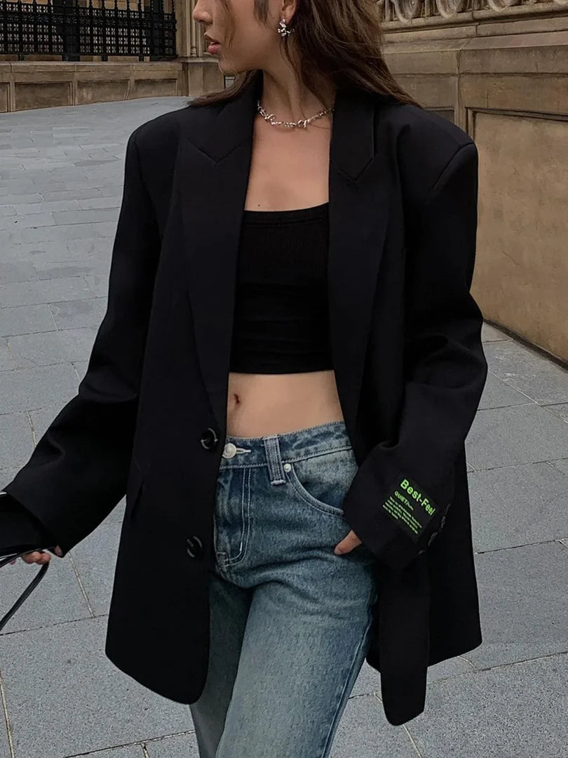 Blazer oversize para mujer en negro combinado con top corto y vaqueros, vista lateral