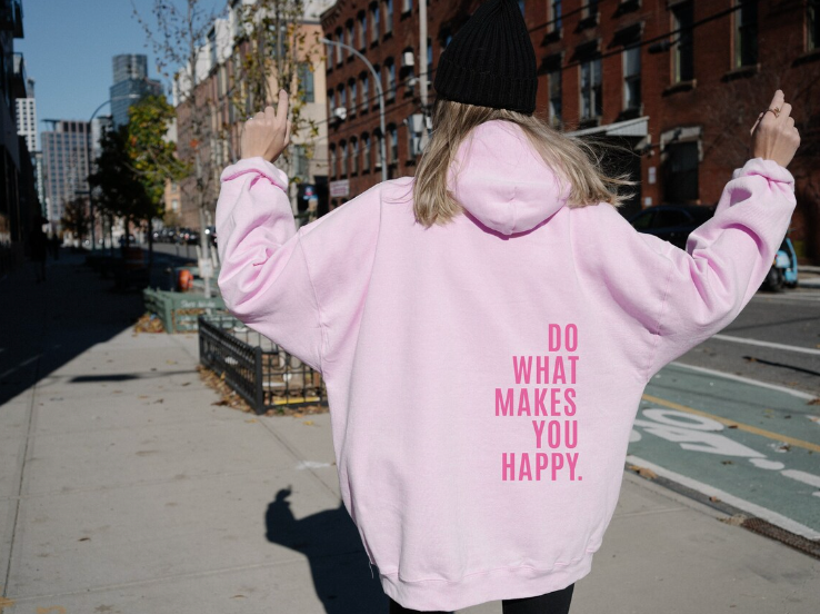 Sudadera oversize para mujer en rosa con mensaje rosa fuerte en la espalda, vista trasera con los brazos levantados